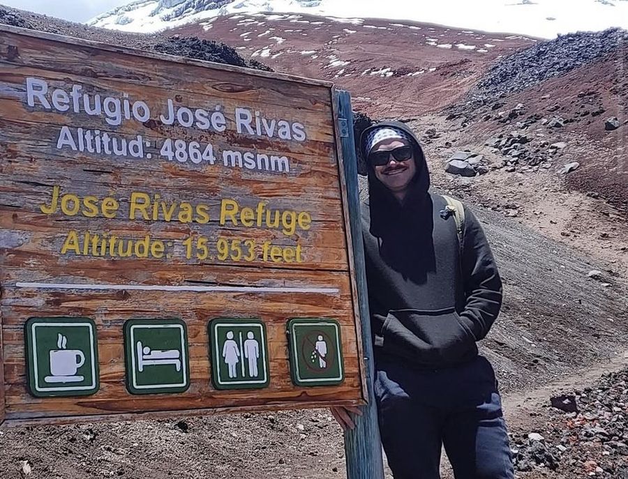 Ian Treger beside the José Rivas Refuge sign on a snow-dusted volcano.