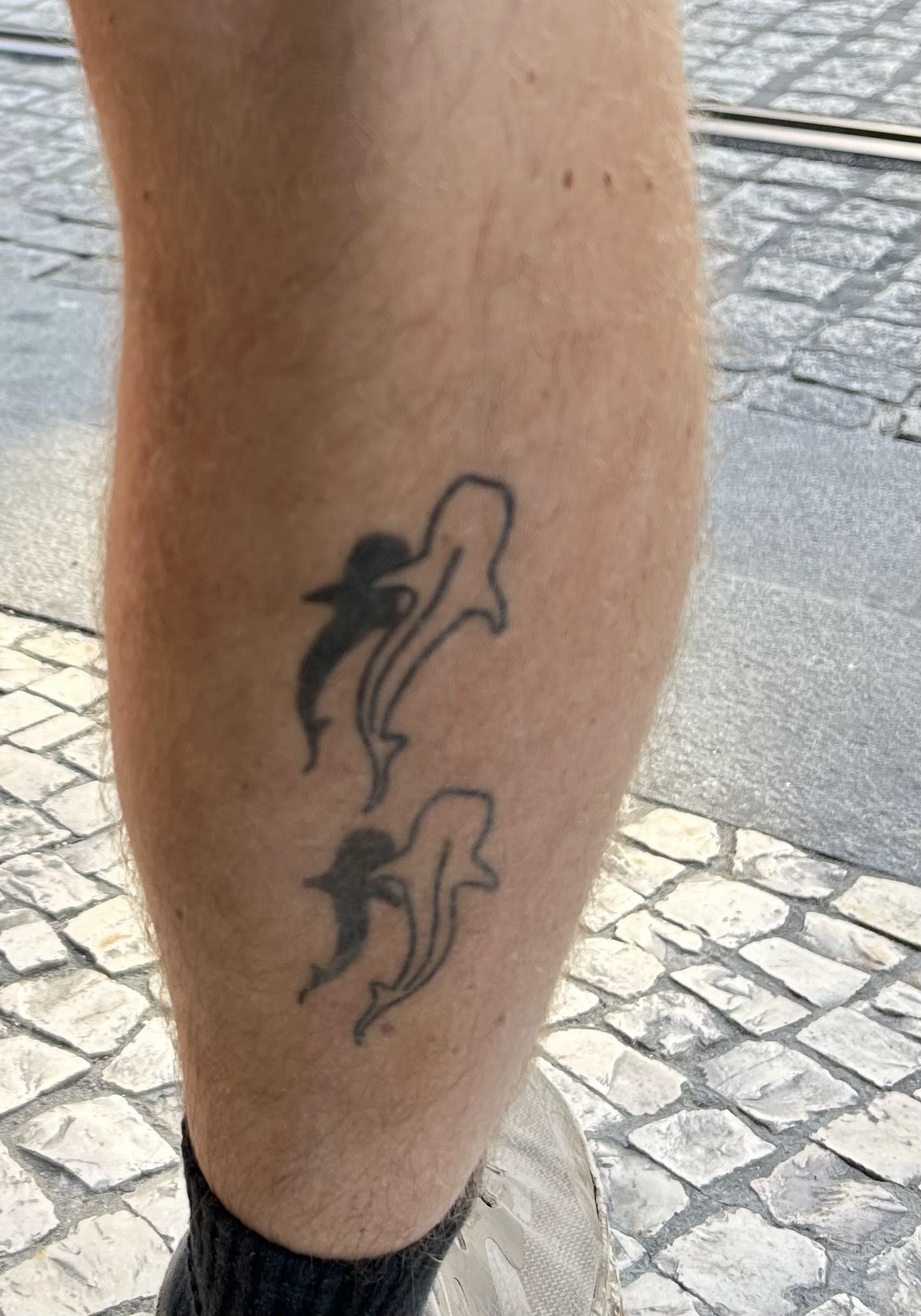 A close-up of two whale shark tattoos on the back of Ian's calf.